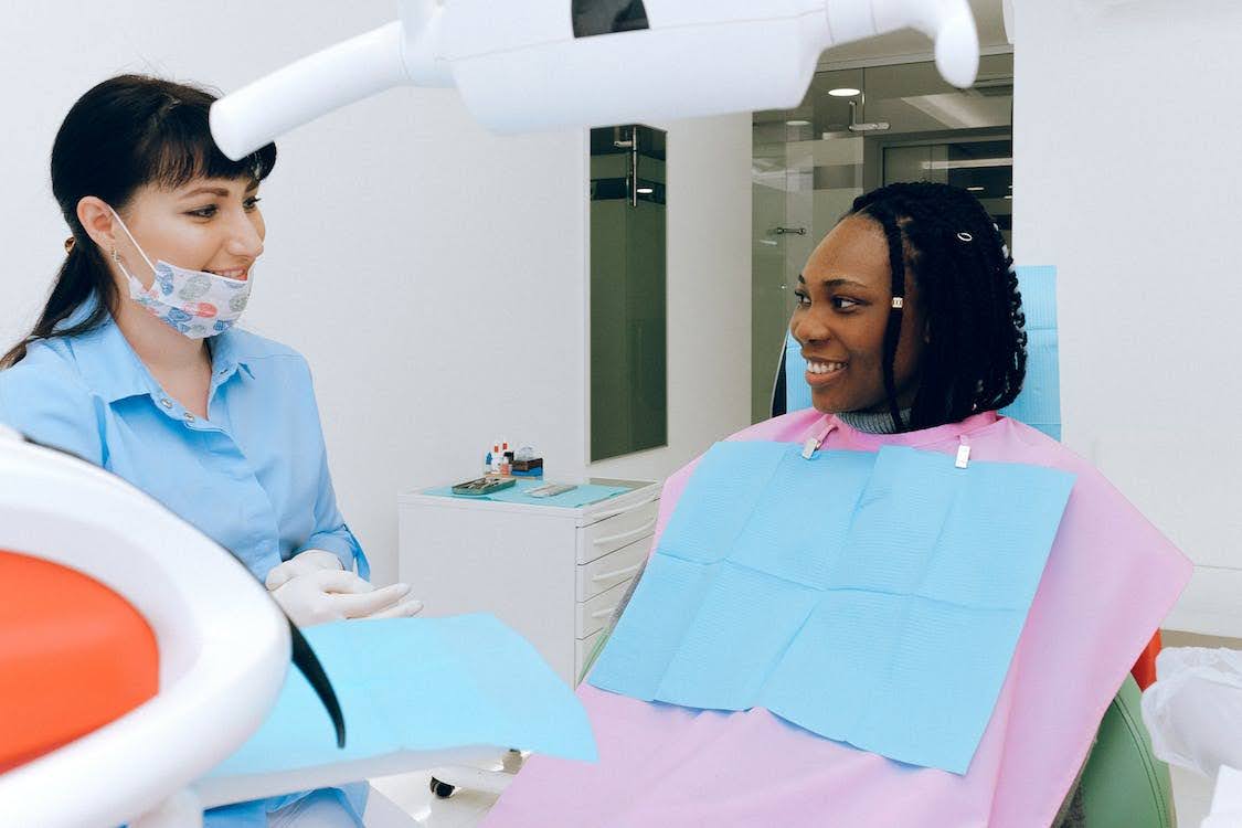 A Simple Guide to Dental Billing and Best Practices You Should Do Dentist and her patient sitting on a dental chair and smiling to each other inside a dental clinic.